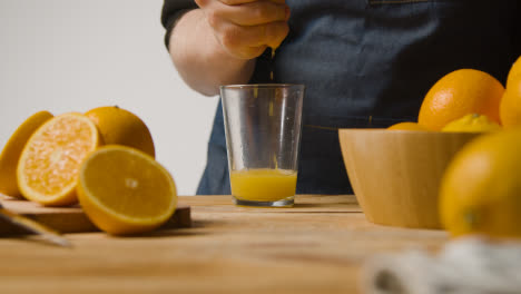 Primer-Plano-Del-Hombre-Cortando-Y-Exprimiendo-Jugo-De-Naranja-En-Un-Vaso