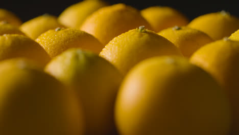 Primer-Plano-De-Estudio-De-Naranjas-Con-Gotas-De-Agua-Girando-Sobre-Fondo-Negro