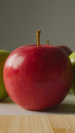 Vertical-Video-Close-Up-Of-Man-Cutting-Fresh-Apples-On-Chopping-Board-