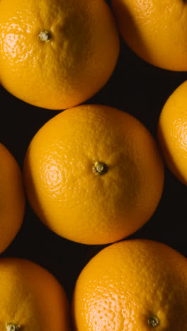 Fotografía-De-Estudio-De-Video-Vertical-De-Naranjas-Girando-Sobre-Fondo-Negro