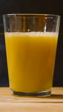 Vertical-Video-Close-Up-Of-Man-Pouring-Fresh-Orange-Juice-Into-Glass-With-Ice