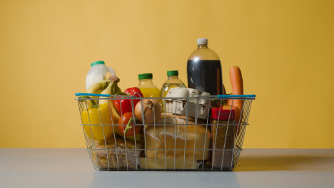 Studio-Shot-Of-Basic-Food-Items-In-Supermarket-Wire-Shopping-Basket-1