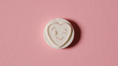 Caramelo-De-Corazón-Con-Emoji-Guiñando-Un-Ojo-Sobre-Fondo-Rosa