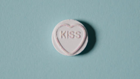 Heart-Candy-With-Word-Kiss-On-Blue-Background