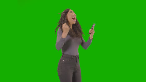 Woman-Looking-At-Mobile-Phone-And-Celebrating-Good-News-Against-Green-Screen-6