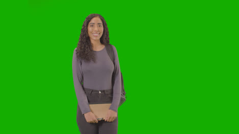 Portrait-Of-Female-College-Or-University-Student-With-Backpack-And-Notebook-Against-Green-Screen-Smiling-At-Camera-1