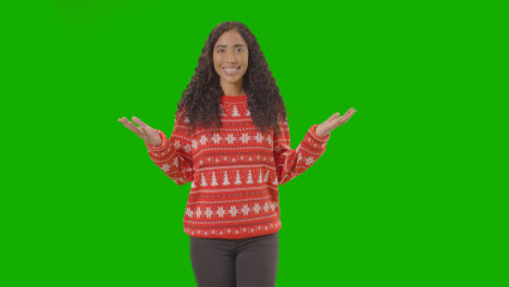 Studioporträt-Einer-Frau-Mit-Weihnachtspullover-Vor-Grünem-Bildschirm,-Die-In-Die-Kamera-Lächelt-Und-Frohe-Weihnachten-Sagt-1