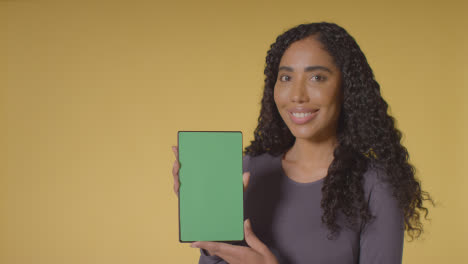 Studioporträt-Einer-Lächelnden-Frau,-Die-Ein-Digitales-Tablet-Mit-Grünem-Bildschirm-Hochhält
