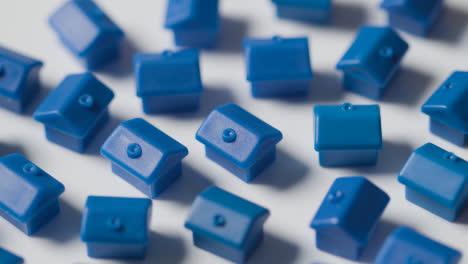 Hauskaufkonzept-Mit-Handräumung-Einer-Gruppe-Blauer-Plastikmodelle-Von-Häusern,-Die-Sich-Auf-Weißem-Hintergrund-Drehen