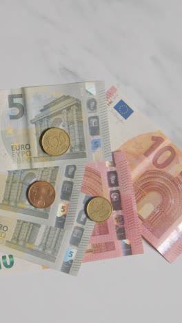 Vertical-Video-Overhead-Currency-Shot-Of-Euro-Notes-And-Coins-Counted-Out-On-Marble-Surface