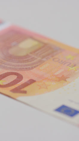 Vertical-Video-Close-Up-Currency-Shot-Of-Hand-Grabbing-10-Euro-Note-On-Marble-Surface