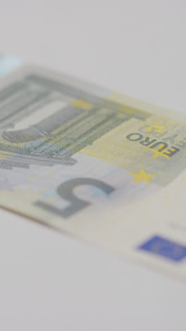 Vertical-Video-Close-Up-Currency-Shot-Of-Hand-Grabbing-5-Euro-Note-On-Marble-Surface