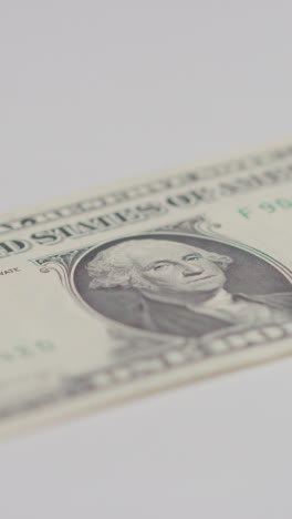 Vertical-Video-Close-Up-Currency-Shot-Of-Hand-Grabbing-US-1-Dollar-Bill-On-Marble-Background