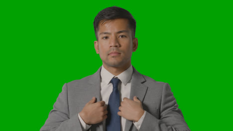 Portrait-Of-Serious-Businessman-Doing-Up-Suit-Jacket-Against-Green-Screen-Looking-At-Camera-1