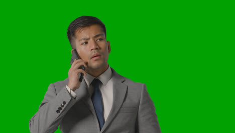 Studio-Shot-Of-Serious-Businessman-In-Suit-Taking-Call-On-Mobile-Phone-Against-Green-Screen-