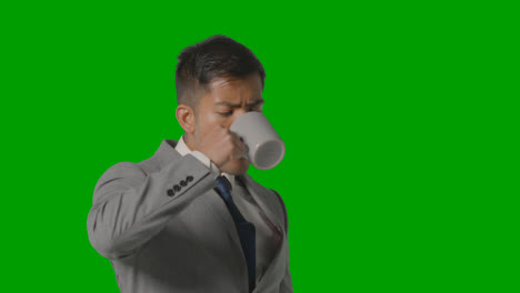 Studio-Shot-Of-Businessman-In-Suit-Holding-Cup-Of-Hot-Drink-Against-Green-Screen-2
