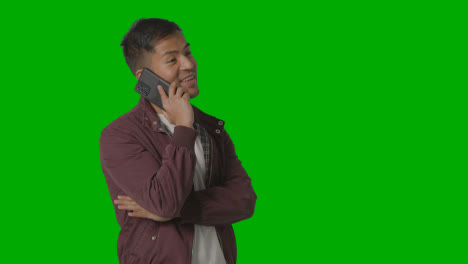 Studio-Shot-Of-Casually-Dressed-Smiling-Young-Man-Taking-Call-On-Mobile-Phone-Against-Green-Screen-2