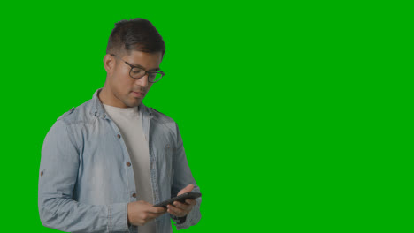 Studio-Shot-Of-Casually-Dressed-Smiling-Young-Man-Taking-Call-On-Mobile-Phone-Against-Green-Screen-3