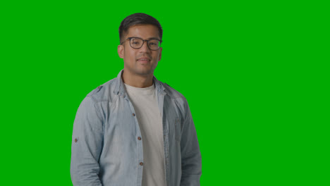 Portrait-Of-Casually-Dressed-Smiling-Young-Man-Wearing-Glasses-Against-Green-Screen-