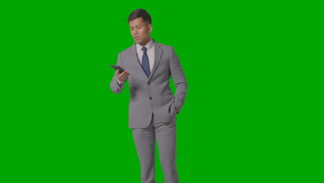 Three-Quarter-Length-Studio-Shot-Of-Unhappy-Businessman-In-Suit-Talking-On-Mobile-Phone-Against-Green-Screen-1