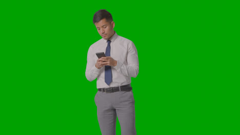 Studio-Shot-Of-Businessman-In-Shirt-And-Tie-Using-Mobile-Phone-Against-Green-Screen-2