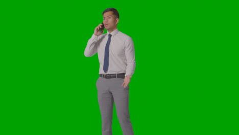 Studio-Shot-Of-Angry-Businessman-In-Suit-Talking-On-Mobile-Phone-Against-Green-Screen-