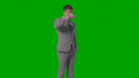 Studio-Shot-Of-Businessman-In-Suit-Holding-And-Drinking-Cup-Of-Hot-Drink-Against-Green-Screen-2