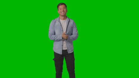 Portrait-Of-Casually-Dressed-Smiling-Young-Man-With-Arms-Outstretched-In-Welcome-Against-Green-Screen-