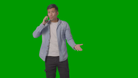 Studio-Shot-Of-Angry-Casually-Dressed-Young-Man-Talking-On-Mobile-Phone-Against-Green-Screen-1