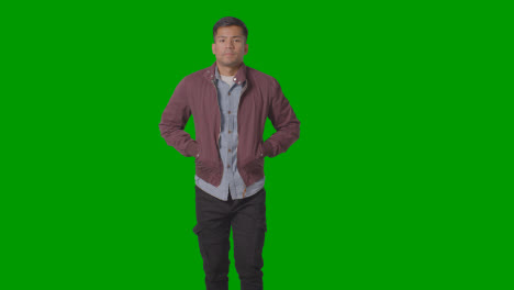 Portrait-Of-Casually-Dressed-Smiling-Young-Man-Putting-Hands-In-Jacket-Lockets-Against-Green-Screen-