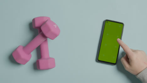 Overhead-Fitness-Studio-Shot-Of-Exercise-Dumbbell-Weights-With-Hand-Using-Green-Screen-Mobile-Phone-1