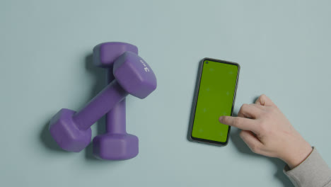 Overhead-Fitness-Studio-Shot-Of-Exercise-Dumbbell-Weights-With-Hand-Using-Green-Screen-Mobile-Phone-3