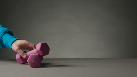 Fitness-Studio-Shot-With-Hand-Picking-Up-Exercise-Dumbbell-Weights-Against-Grey-Background-2