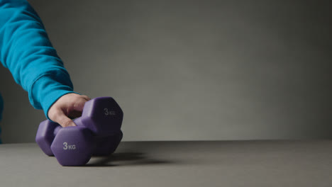 Fitness-Studio-Shot-With-Hand-Picking-Up-Exercise-Dumbbell-Weights-Against-Grey-Background-9