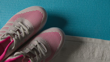 Overhead-Studio-Fitness-Shot-Of-Rotating-Trainers-With-Towel-On-Blue-Exercise-Mat