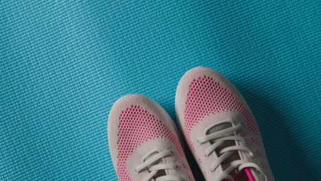 Overhead-Studio-Fitness-Shot-Of-Rotating-Trainers-On-Blue-Exercise-Mat-With-Lighting-Fading-Up-And-Down
