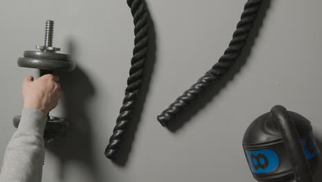 Overhead-Studio-Fitness-Shot-Of-Battle-Rope-On-Grey-Background-With-Hand-Picking-Up-Gym-Weight-2