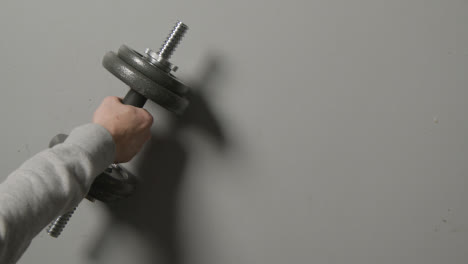 Overhead-Studio-Fitness-Shot-Of-Hand-Picking-Up-Gym-Weight-On-Grey-Background-1