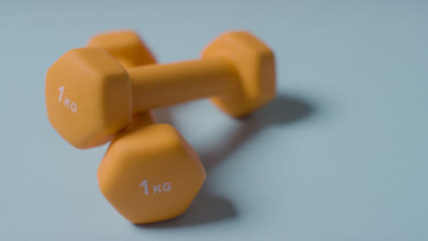 Close-Up-Fitness-Studio-Shot-Of-Yellow-Exercise-Dumbbell-Weights-Against-Blue-Background