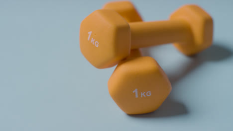 Close-Up-Fitness-Studio-Shot-Of-Yellow-Exercise-Dumbbell-Weights-Against-Blue-Background