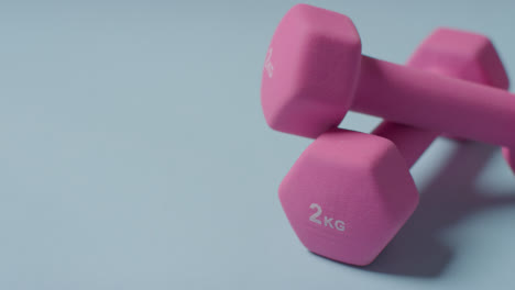 Close-Up-Fitness-Studio-Shot-Of-Pink-Exercise-Dumbbell-Weights-Against-Blue-Background