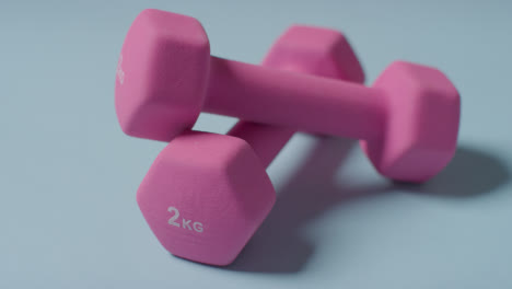 Close-Up-Fitness-Studio-Shot-Of-Pink-Exercise-Dumbbell-Weights-Against-Blue-Background-1