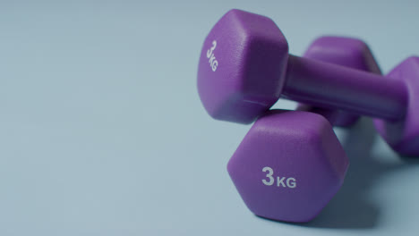 Close-Up-Fitness-Studio-Shot-Of-Purple-Exercise-Dumbbell-Weights-Against-Blue-Background