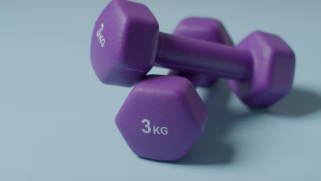 Close-Up-Fitness-Studio-Shot-Of-Purple-Exercise-Dumbbell-Weights-Against-Blue-Background-1