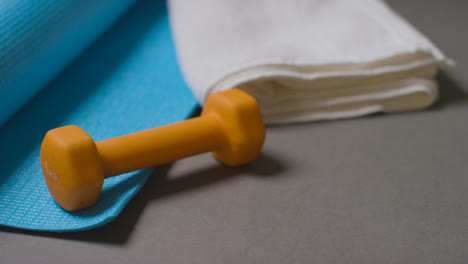 Close-Up-Fitness-Studio-Shot-Of-Male-Hand-Putting-Down-Exercise-Dumbbell-Weight-And-Water-Bottle-With-Towel-And-Mat