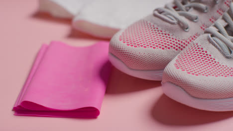 Studio-Fitness-Shot-With-Trainers-Resistance-Band-And-Towel-On-Pink-Background