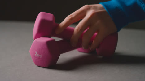 Close-Up-Studio-Fitness-Shot-Of-Hand-Picking-Up-Pink-Gym-Weight-On-Grey-Background-1