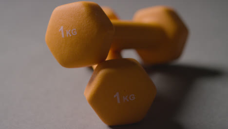 Close-Up-Studio-Fitness-Shot-Of-Yellow-Gym-Hand-Weights-On-Grey-Background