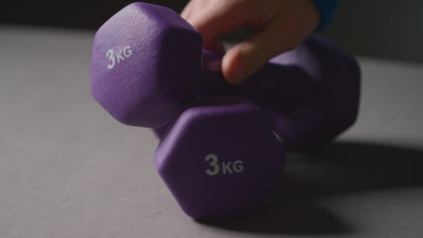 Close-Up-Studio-Fitness-Shot-Of-Hand-Picking-Up-Purple-Gym-Weight-On-Grey-Background