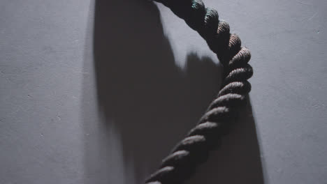 Close-Up-Studio-Fitness-Shot-Of-Gym-Battle-Rope-On-Grey-Background-Against-Bright-Light-1